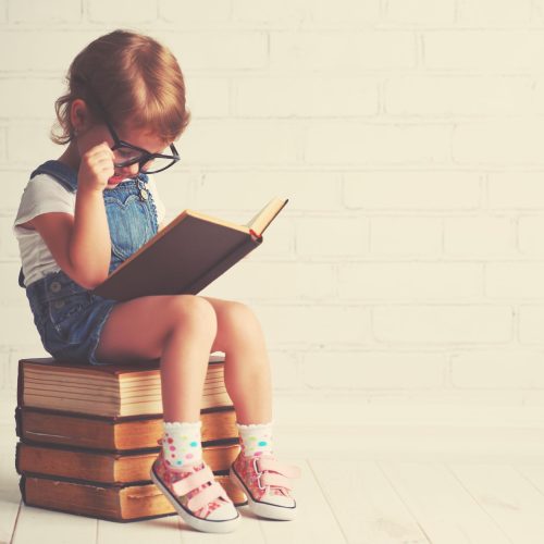 Happy,Child,Little,Girl,With,Glasses,Reading,A,Books